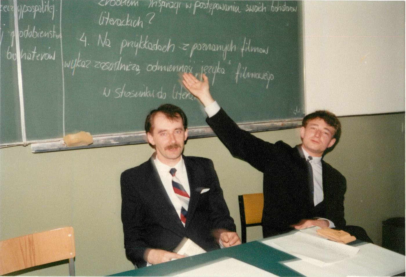 Учитель показывает на доске темы сочинений, рядом сидит коллега