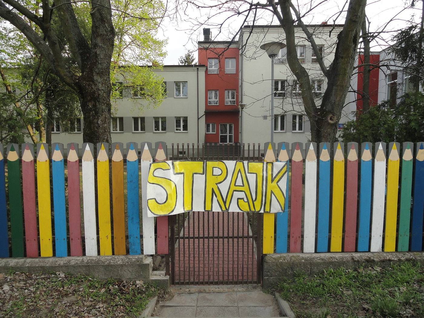 Разноцветный забор в виде карандашей с плакатом «STRAJK»